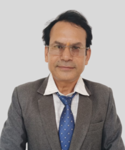 Head-and-shoulders portrait of a man in a gray suit, white shirt, and blue tie, wearing glasses and facing the camera against a light gray background.